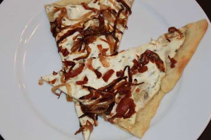 Flammkuchen is a German thin crust pizza with crispy bacon and onions with a sour cream/greek yogurt sauce.